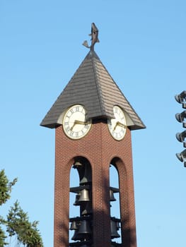 Bell Tower and clock strike quarter past the hour in a downtown city square.
