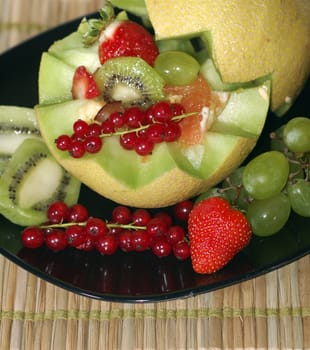 a dish of fruit served in a black dish with tropical style