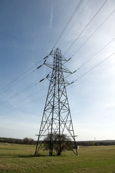 An electrical pylon in a field with a blue sky