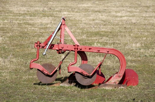 An old plough in a field of grass