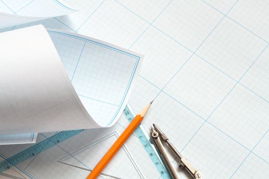 Divider, pencil and ruler on blue graph paper background