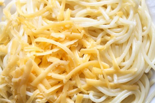 Extreme closeup of grated cheese lying on spaghetti background