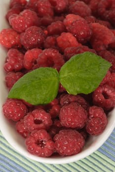 Fresh raspberries with leaves on a white plate