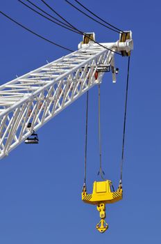 Crane arm with yellow hook against a blue sky