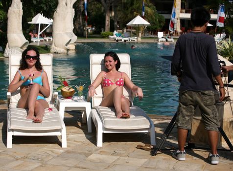 Two young girls with cocktails near the swimming pool