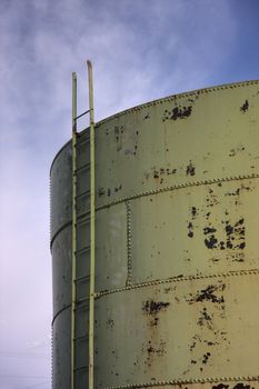 a ladder to the top of an old storage tank or grain bin (metal sheets joined with rivets) against sky