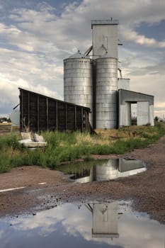 Old abandoned grain elevator and shack in Colorado farmland.  Water reflection.