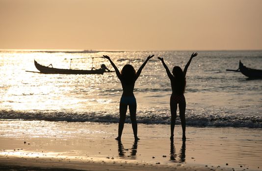 Two silhouettes of girls at coast of ocean