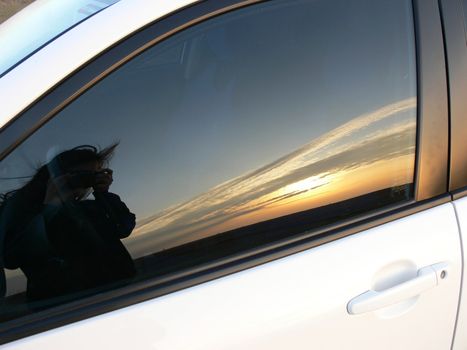 Reflection of sunset and girl in car's window