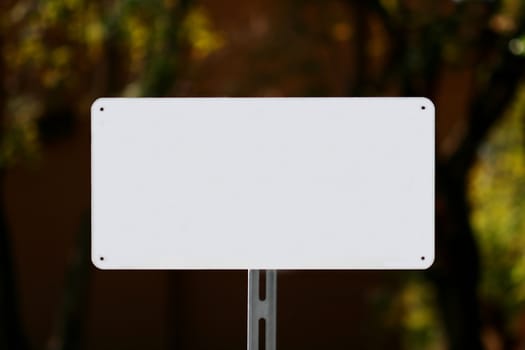 White sign with a natural green and dark brown background.