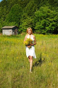 blond woman in white dress walking through the meadow