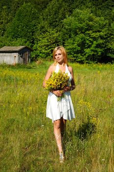 blond woman in white dress walking through the meadow