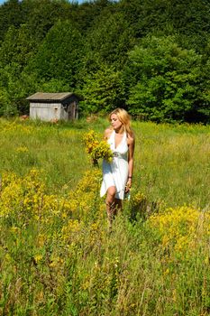 blond woman in white dress walking through the meadow