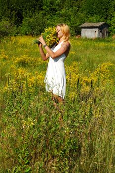 blond woman in white dress smelling bunch of flowers