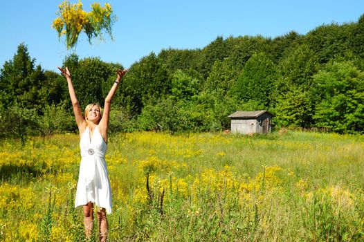 blond woman in white dress throwing bunch of flowers