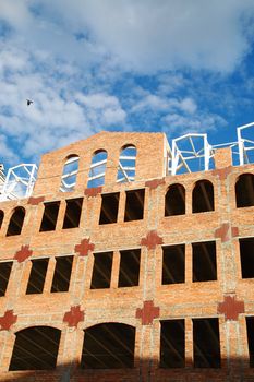 building of red brick under construction and blue sky in window frames