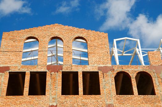 building of red brick under construction and blue sky in window frames