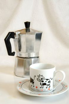 white cup with picture of cow against coffee-maker