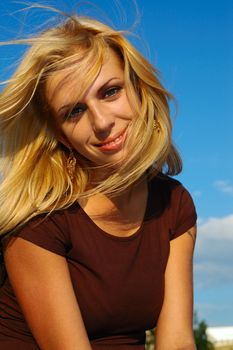 Smiling blond woman with fly-away hair against blue sky