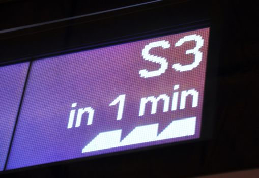 Part of a digital newsboard announcing the arrival of the next train in one minute