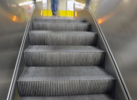 Foto of an escalator moving down from a bright yellow floor