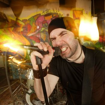 Metal singer cussing into the microphone.  Shot with strobes and slow shutter speed to create lighting atmosphere and blur effects.
