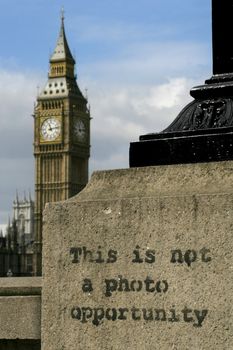 Graffiti on a lamp-post across the Thames river from Big Ben in London.  Big Ben is slighty out of focus in the distance while the graffiti is in focus.

