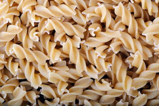 Fusilli twirls pasta. Italian food background. Whole wheat.