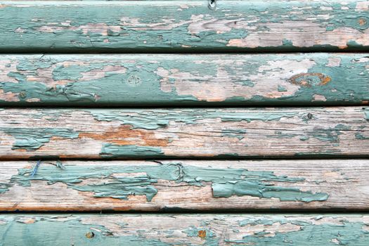 An old wooden wall texture with peeling faded green paint