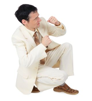 Businessman sitting in a defensive posture on a white background