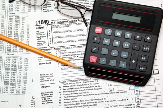 Tax time - Closeup of U.S. 1040 tax return with pencil, glasses and calculator