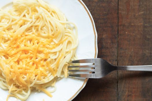 Plate with spaghetti and grated cheese on wooden background