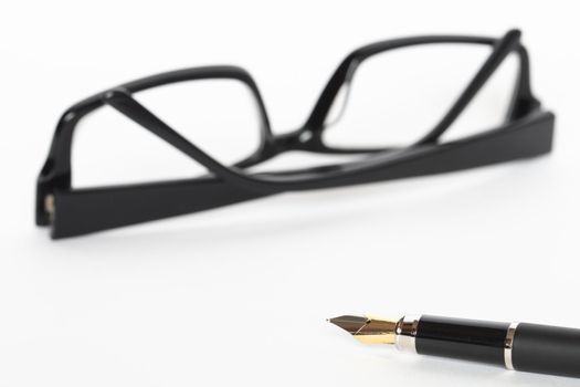 Closeup of fountain pen lying on white background with black spectacles