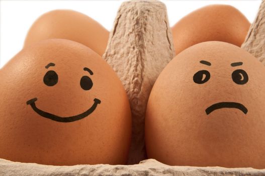Close and low level capturing two eggs with painted faces arranged in carton against white background