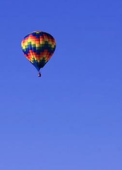 Colorful hot air balloon in brilliant blue sky with plenty of copy space