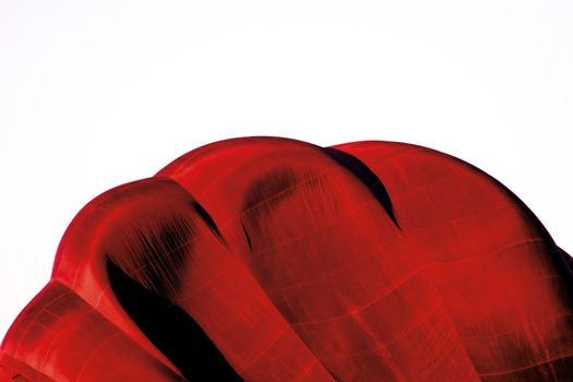 Red and white abstract image of hot air balloon inflating with plenty of copy space.