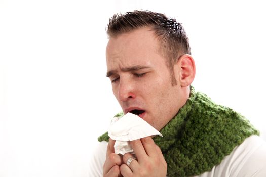 Man suffers from allergies or the flu. He blows his nose when he sneezes