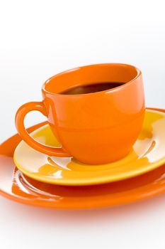 Orange coffee cup with yellow plate over white background