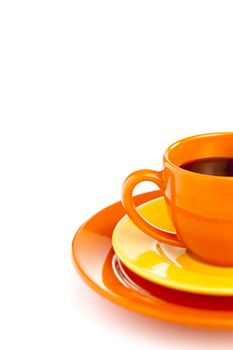 Orange coffee cup with yellow plate over white background