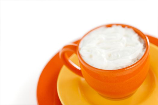 Orange coffee cup with yellow plate over white background