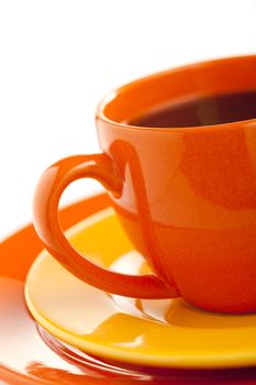 Orange coffee cup with yellow plate over white background