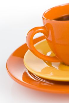 Orange coffee cup with yellow plate over white background