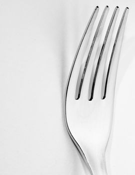 Macro shot of a dining fork over a white backdrop