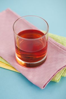 Glass of cranberry juice on pile of napkins