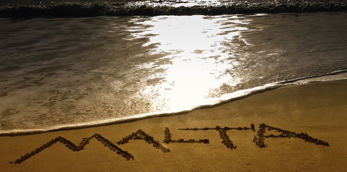 The word Malta spelled out in the sand at Golden Bay in Malta