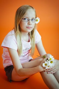 Young girl sitten on the  orange background