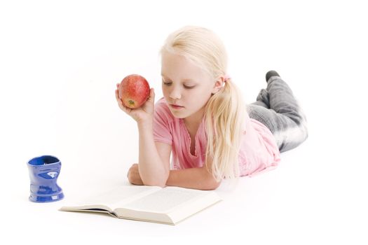 Young girl reading a book and eating an apple