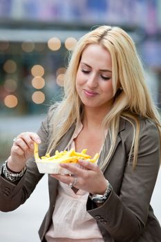 Pretty blond girl dipping her fries in the mayonaise