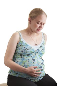 A pregnant young woman sitting on a white background. 