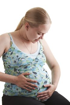 A pregnant young woman sitting on a white background.